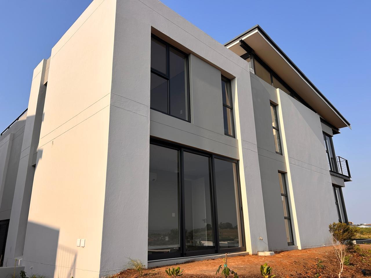 White rendered double-storey home with double-volume black-framed windows and sliding doors