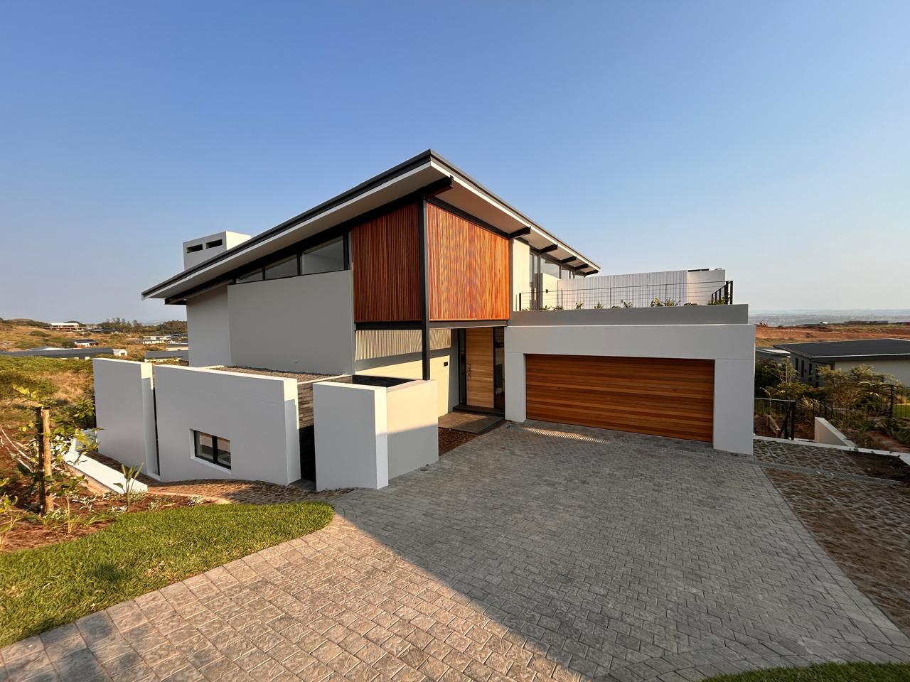 Contemporary double-storey home with a timber slat screen, cedar garage door and paved driveway, built by Green Living Projects
