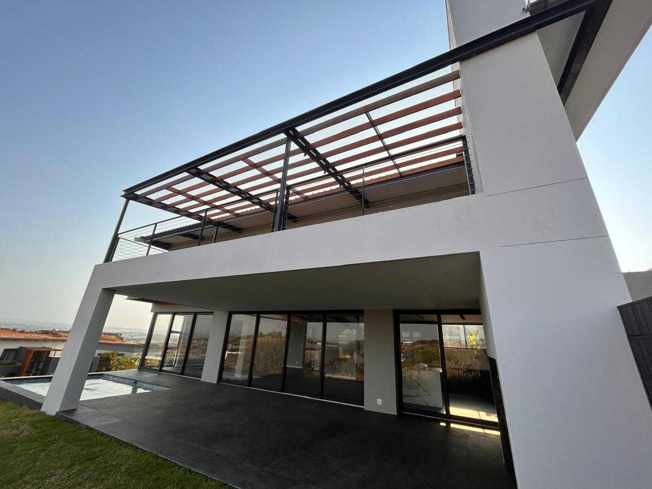 Upper balcony with a steel and timber pergola above a covered tiled patio next to a swimming pool