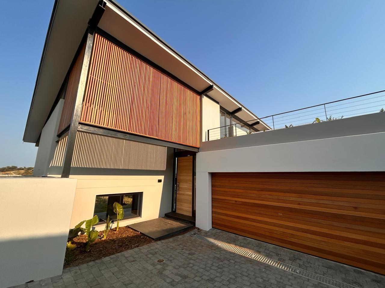 Modern home entrance with a vertical timber slat screen, timber front door and cedar garage door